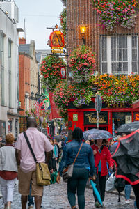 Rear view of people walking on street against buildings