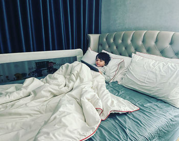 Midsection of boy resting on bed at home