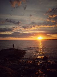 Silhouette person on beach against sky during sunset