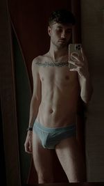 Side view of young woman standing against wall