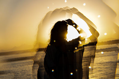 Rear view of woman standing against sky during sunset