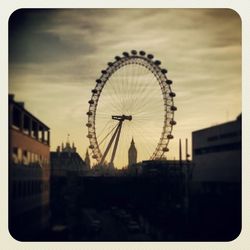 Low angle view of ferris wheel against cloudy sky
