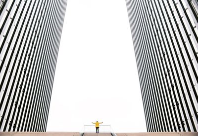 Full length of man standing on staircase amidst buildings against clear sky