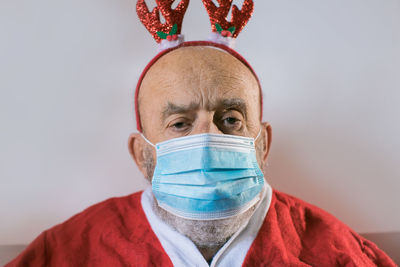 Portrait of senior man wearing mask sitting at home