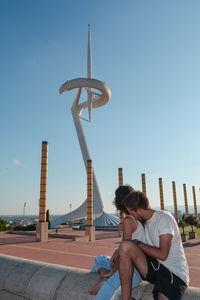 Man sitting at observation point against clear sky