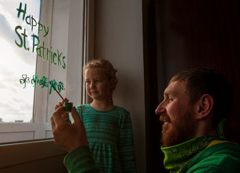 Drawing st. patrick's day father daughter painting green three-leaved shamrocks.stay home new normal