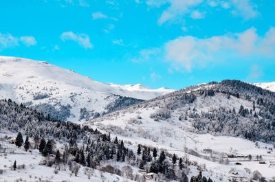 Scenic view of snowcapped mountains against blue sky