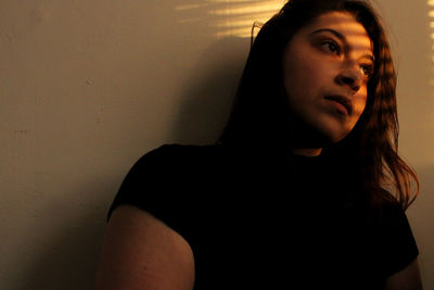 Portrait of beautiful young woman against wall