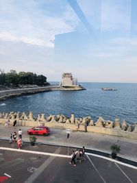 People on road by sea against sky