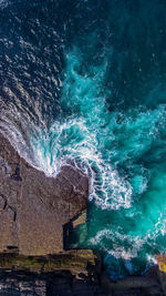 High angle view of sea waves splashing on rocks