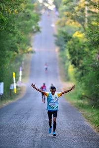 Rear view of boy running on road