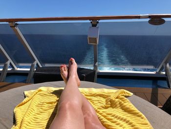 Low section of woman relaxing on sea against sky