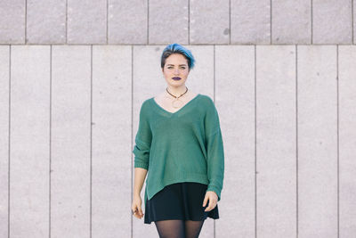 Portrait of woman standing against wall