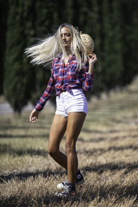 Young woman walking on grassy land during sunny day