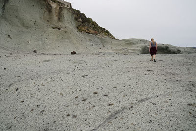 Woman walking on land against mountain