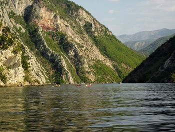 Scenic view of sea by mountains against sky