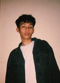 Portrait of young man standing against wall