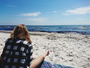 Rear view of woman on beach against sky