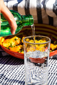 Close-up of hand pouring water in glass on table