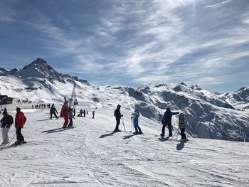 People skiing on snowcapped mountain against sky