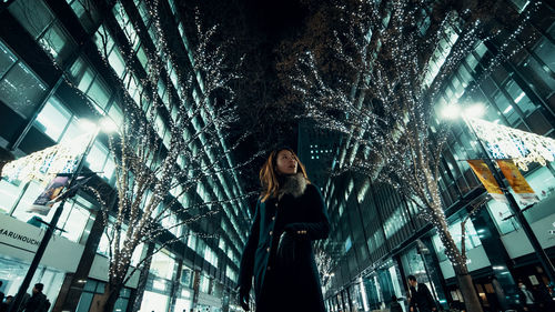 Low angle view of woman looking at illuminated tree