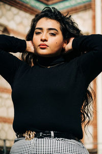 Portrait of young woman standing against wall