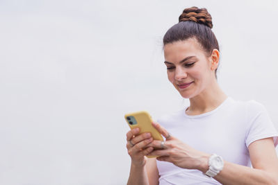 Young woman using mobile phone against white background