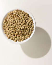 High angle view of coffee beans in bowl against white background