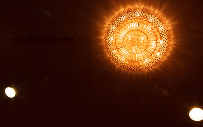 Low angle view of illuminated chandelier hanging against sky