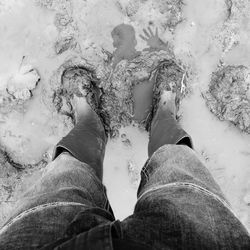 Low section of man standing in mud