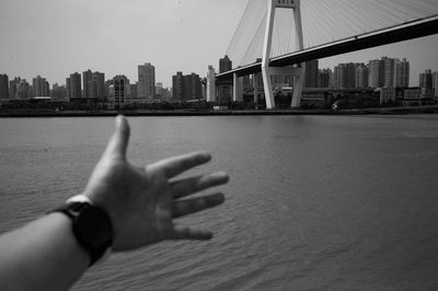 Cropped image of person by river against buildings in city