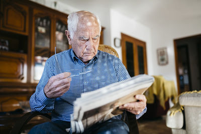 Senior man reading newspaper at home