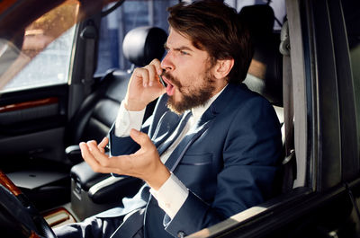 Young man using mobile phone while sitting in car