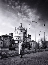 Rear view of man walking on street by basilica di san lorenzo against sky