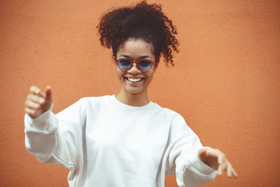 Portrait of young man wearing sunglasses against wall