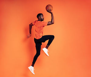 Smiling athlete holding basketball against colored background