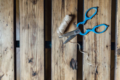 Directly above shot of thread spool with scissors on wooden table