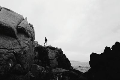 Low angle view of man standing on cliff against clear sky