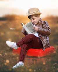 Rear view of smiling boy sitting outdoors