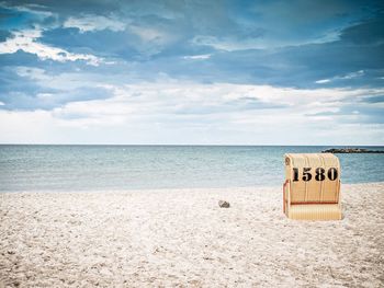 Hooded chair at beach against sky