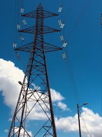 Low angle view of electricity pylon against blue sky