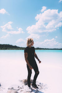 Full length of woman standing by lake against sky