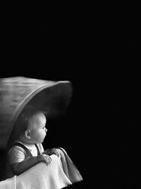 Side view of woman standing against black background