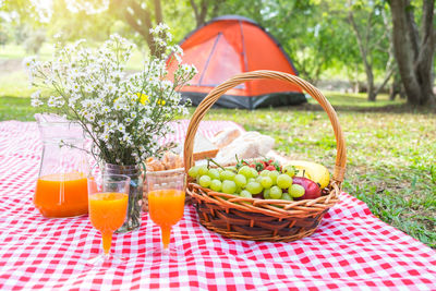 Fruits in basket by orange juices in park