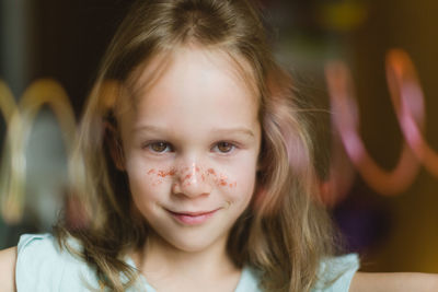 Portrait of positive adorable girl with glitters on face looking at camera during party