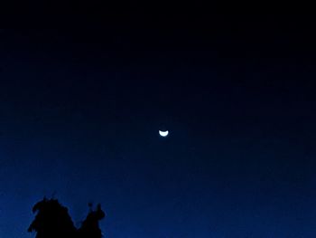 Low angle view of silhouette moon against blue sky at night