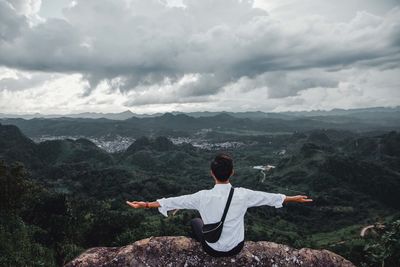 Rear view of man looking at mountains against sky