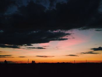 Silhouette landscape against dramatic sky during sunset