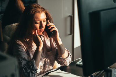 Young woman using mobile phone while sitting at home