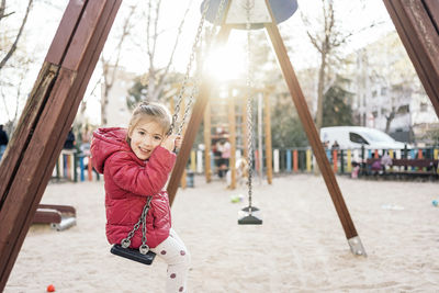 Portrait of girl sitting on swing at park